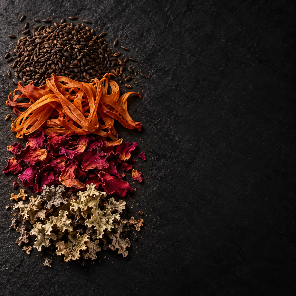 The key ingredients of Chicken Biryani Masala, laid out on slate: black cumin, mace, dried rose petal and stone flower